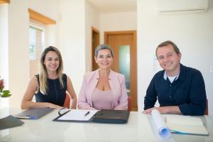 Three professionals smiling at a business meeting in a modern office.